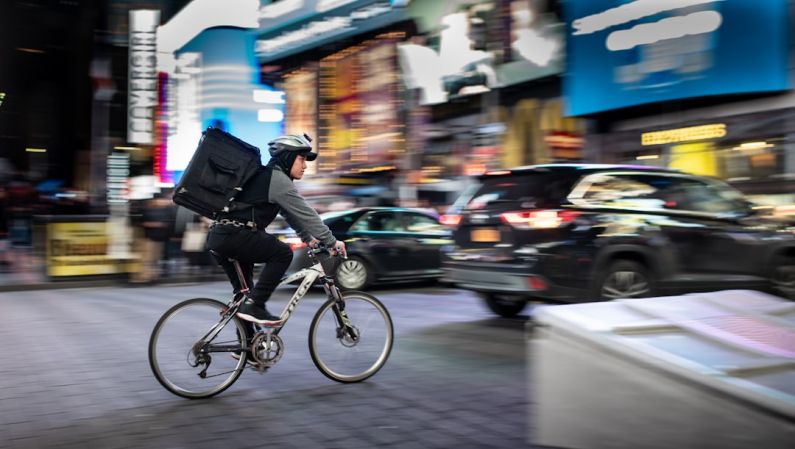 Fast Delivery - man riding bicycle near vehicles